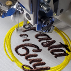 Embroidery machine stitching text and a yellow circle on fabric