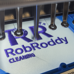 Embroidery machine needle plate with 'Rob Roddy Cleaning' text