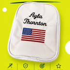 A white zippered golf bag with embroidered text reading 'Ayla Thornton' and an American flag patch, shown on a bright yellow-green background with large text reading 'GOLF BAG EMBROIDERY' and a 'Gaspar Stitch' label at the top.